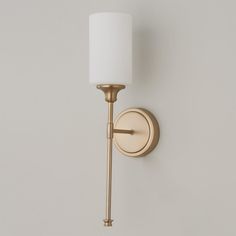 a wall mounted light with a white shade on it's side and a gold arm