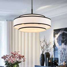 a chandelier hanging over a dining room table with vases and flowers on it