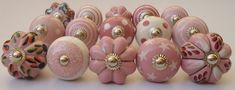 a bunch of pink and white glass knobs with gold decorations on them, all lined up together