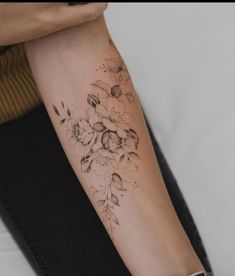 a woman's arm with flowers and leaves tattooed on the left side of her arm