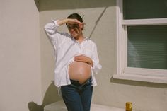 a pregnant woman is standing in front of a house with her hands on her head