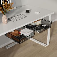 a computer desk with drawers underneath it and a keyboard on the other side, in front of a flower vase