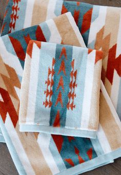 three towels folded on top of each other with red, blue and orange designs in them