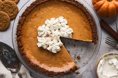 there is a pie with whipped cream on top and pumpkins around the edges next to it