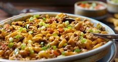 a bowl filled with macaroni and cheese on top of a table next to chips