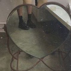 a woman standing in front of a mirror with her legs on the table and wearing black boots