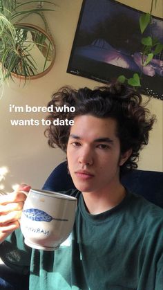 a young man holding a coffee cup in his hand with the words i'm bored who wants to date