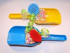 two plastic spoons with candy in them on top of a blue tray next to each other