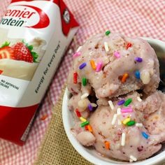 two scoops of ice cream with sprinkles in a bowl next to a carton of milk