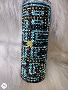 a blue and black beaded travel mug on white fur