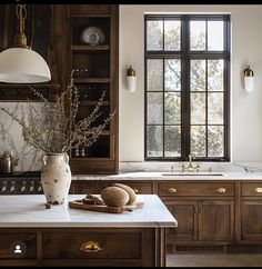 a kitchen with marble counter tops and wooden cabinets, along with a vase filled with flowers