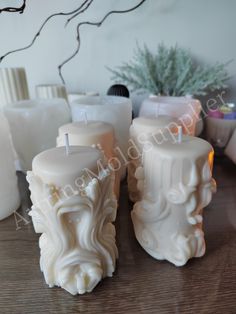 three white candles sitting on top of a wooden table