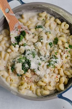 a wooden spoon in a pot filled with macaroni and cheese