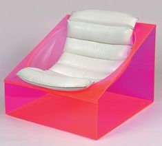 a pink and white chair sitting on top of a plastic box with an inner cushion