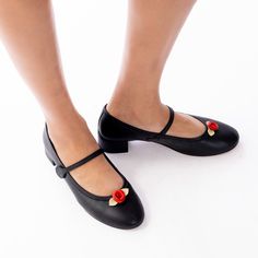 The ultimate classic Mary Jane, made perfectly in soft nappa leather and topped with a pretty handmade leather rosette, a la Kitteny style. We love our details - lined in red gingham, cushy insoles, panel at the heel to prevent blisters, leather binding around the top, and our paw print soles. Straps have elastic on the inside and a velcro closure on the outer side of the shoe. Sustainability/ethics: The premium leather is ethically sourced and naturally dyed, no harmful chemicals. The plastic u Spring Court Shoes With Red Sole And Round Toe, Spring Leather Dance Shoes With Leather Sole, Leather Dance Shoes With Rubber Heel Cap, Spring Mary Jane Court Shoes With Rubber Sole, Leather Mary Jane Dance Shoes With Closed Toe, Spring Dance Shoes With Leather Sole And Almond Toe, Spring Leather Closed Toe Dance Shoes, Spring Leather Dance Shoes With Round Toe, Spring Leather Dance Shoes With Closed Toe