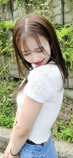 a girl with long brown hair wearing a white shirt and blue jeans is posing for the camera