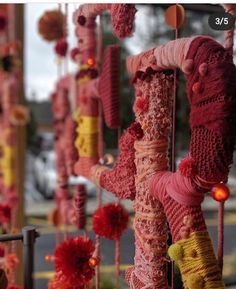 many knitted objects are hanging from poles