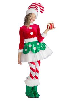 a woman dressed in an elf costume holding a christmas present and smiling at the camera