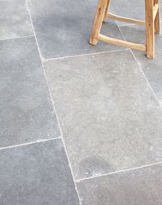 a wooden stool sitting on top of a stone floor