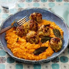 meatballs and mashed potatoes in a blue bowl with sage leaves on the side