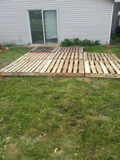 a wooden pallet sitting in the grass near a house