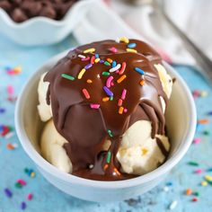 a scoop of ice cream with chocolate and sprinkles in a white bowl