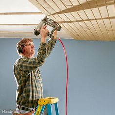 a man is painting the ceiling in his room with headphones and a paint roller