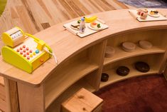 a wooden counter topped with lots of plates and bowls next to a phone on top of a shelf