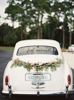 an old white car with flowers on the back and lettering that reads,'just married '