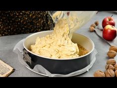 a person pouring batter into a bowl filled with nuts