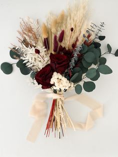 a bouquet of dried flowers and greenery on a white background