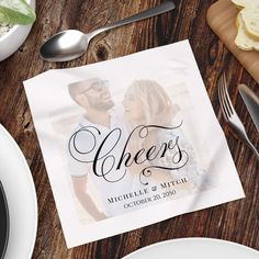 a table topped with plates and silverware next to a napkin that says cheers on it