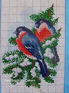 a blue bird sitting on top of a tree branch in front of a cross stitch pattern