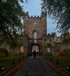 two people are standing in front of an old castle