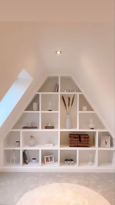 an attic bedroom with white shelving in the corner and a rug on the floor