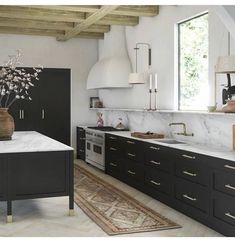 a kitchen with marble counter tops and black cabinets, along with an area rug on the floor