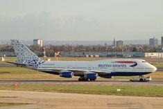 a british airways plane on the tarmac at an airport in england, with buildings in the background