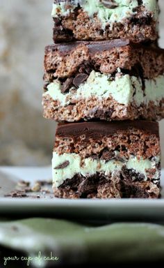 four pieces of chocolate and mint ice cream cake stacked on top of each other in front of a plate