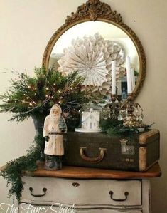 an old suitcase is sitting on top of a dresser with christmas decorations and greenery