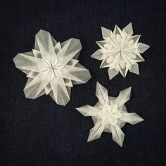 three white paper snowflakes sitting on top of a black surface