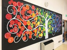 an art piece is displayed on the wall in a school hallway, with trees painted on it