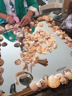 a table with seashells on it and a person cutting them into small pieces