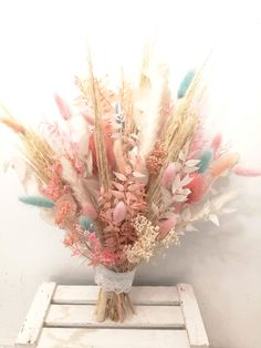 a vase filled with lots of different colored feathers on top of a white table next to a wall