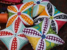 three decorative pillows with colorful designs on them sitting next to some thread spools