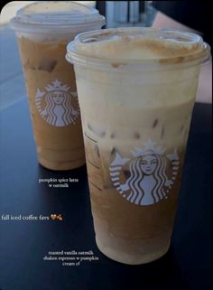 two cups of iced coffee sitting on top of a black table next to each other