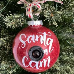 a red ornament hanging from a christmas tree with the words santa cam on it