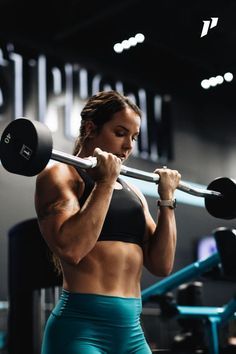 a woman lifting a barbell in a gym