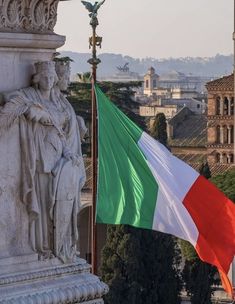 an italian flag flying in front of a statue