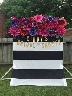 a black and white striped chair with flowers on it in front of a wooden fence