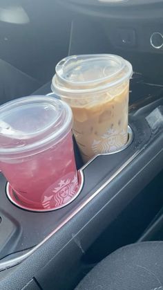 two cups of coffee sit on the dashboard of a car, next to each other